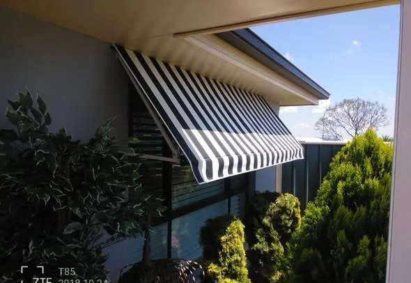 Striped folding-arm awning over a garden window